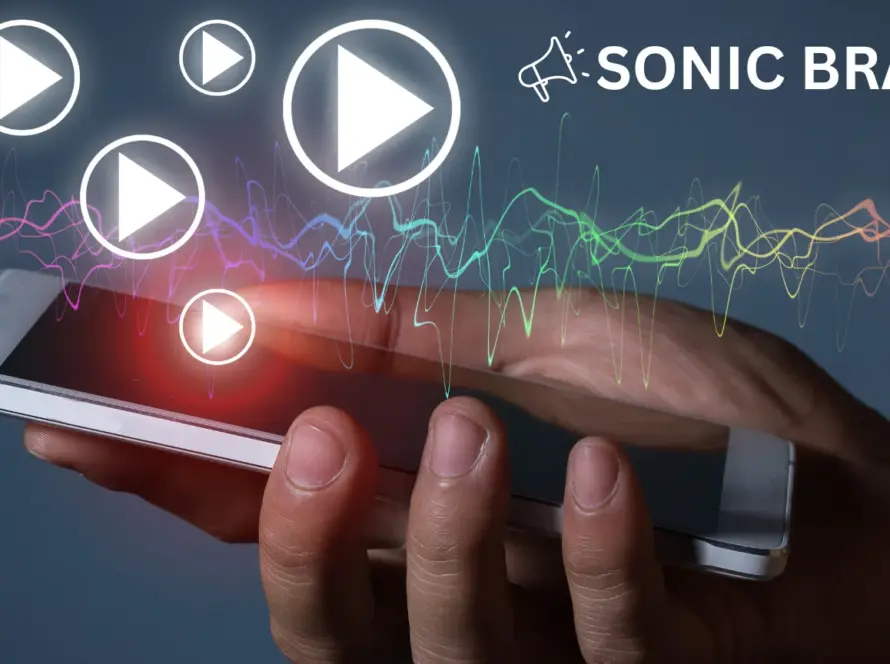 Hand hält ein Smartphone mit leuchtenden Play-Symbolen und einer farbigen Klangwelle darüber, begleitet von der Aufschrift 'Sonic Branding'.