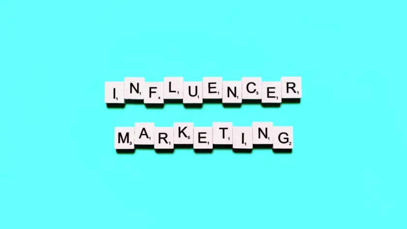 Das Wort 'Influencer Marketing' aus Scrabble-Buchstaben auf einem türkisfarbenen Hintergrund.